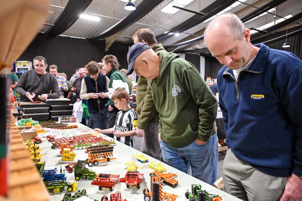 Visitors browsing boxed model tractors at a trade stand