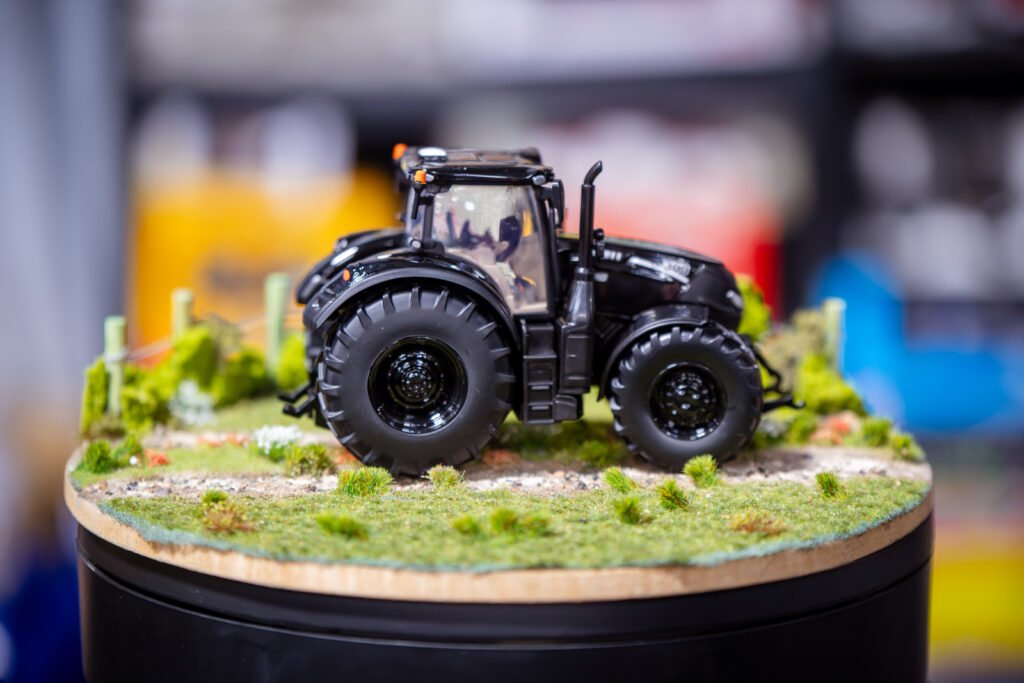 Black tractor model displayed on a round grass diorama base at the Spalding Model Tractor Show