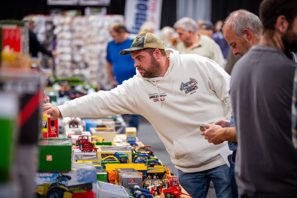 Trader reaching across a table of boxed farm and construction models at the Spalding Model Tractor Show