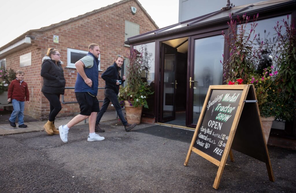 Visitors arriving at the Spalding Model Tractor Show past the chalkboard entrance sign