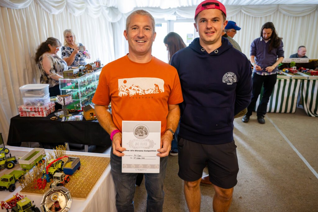 A competition winner with his certificate beside his diorama