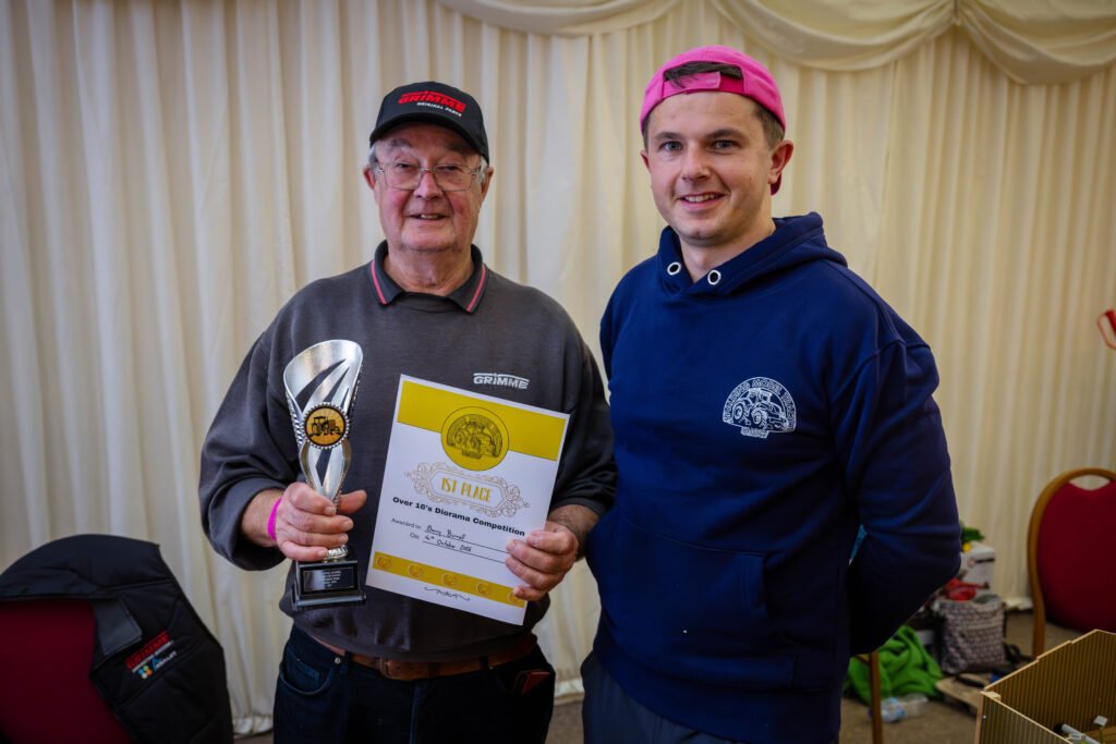 A diorama competition winner holding his trophy and certificate