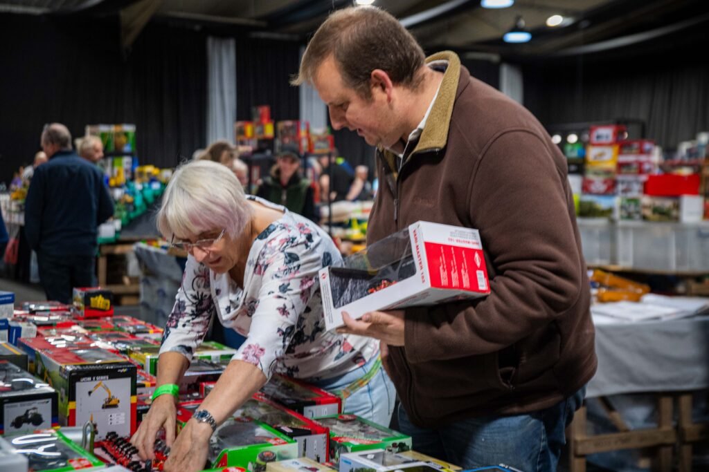 Two visitors looking over boxed models on a trade table