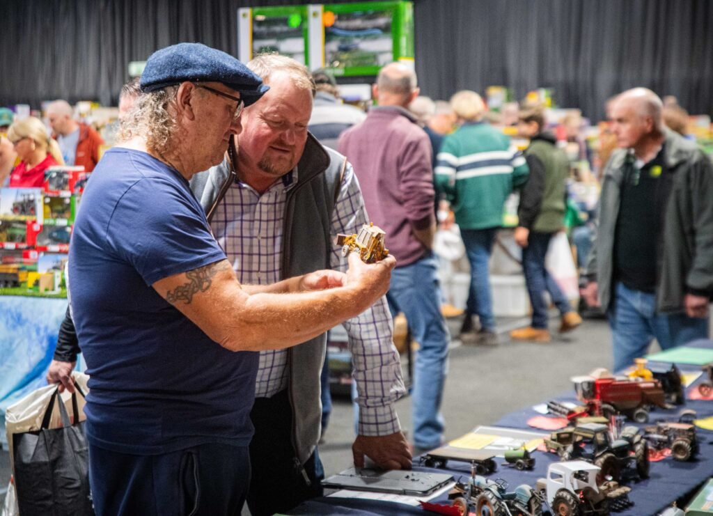 Two visitors looking closely at a model tractor