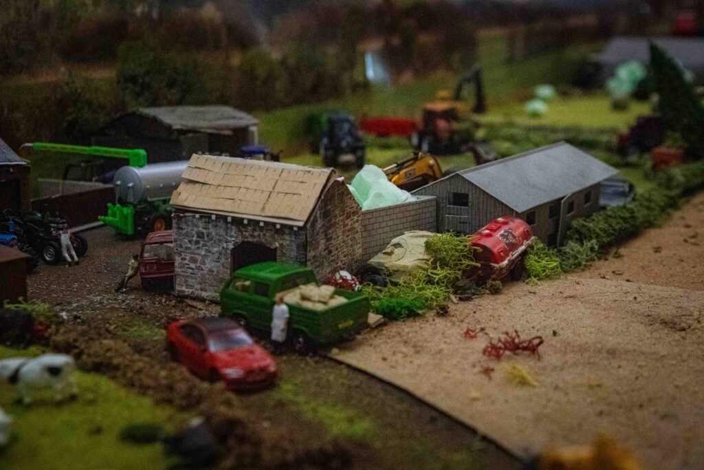 A farmyard diorama with a stone barn and model machinery