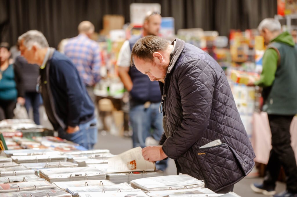 A visitor browsing models in a busy aisle of the show